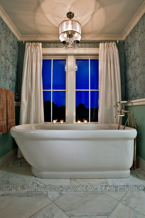 Saratoga Springs-based Teakwood Builders bathroom lighting design idea book: This luxurious freestanding soaking tub surrounded by marble, serene blue paint and wall paper, is crowned by its crystal and polished nickel light fixture. Teakwood Builders, kitchen and bath remodeler, custom home builder and general contractor Saratoga Springs and Capital Region.