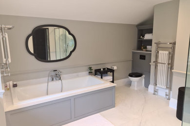 Photo of a large traditional ensuite bathroom in London with shaker cabinets, grey cabinets, a built-in bath, porcelain tiles, quartz worktops, double sinks and a built in vanity unit.