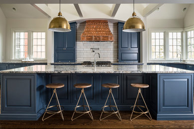 Mid-sized contemporary l-shaped open plan kitchen in Cincinnati with raised-panel cabinets, blue cabinets, subway tile splashback, dark hardwood floors, with island, a double-bowl sink, granite benchtops, white splashback, panelled appliances, brown floor and grey benchtop.