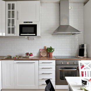 Inspiration för ett skandinaviskt brun brunt kök, med skåp i shakerstil, vita skåp, träbänkskiva, vitt stänkskydd, stänkskydd i tunnelbanekakel och rostfria vitvaror