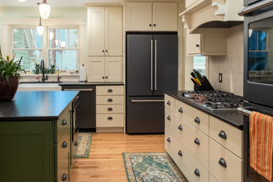 Example of a mid-sized l-shaped light wood floor eat-in kitchen design in Other with an undermount sink, shaker cabinets, white cabinets, quartz countertops, white backsplash, subway tile backsplash, stainless steel appliances, an island and black countertops
