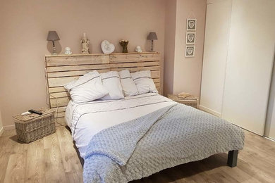 Inspiration pour une chambre d'amis style shabby chic de taille moyenne avec un mur rose, sol en stratifié, aucune cheminée et un sol marron.