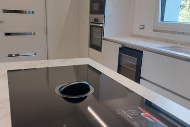 Foto di una grande cucina moderna con lavello sottopiano, ante lisce, ante bianche, top in superficie solida, elettrodomestici in acciaio inossidabile e top multicolore