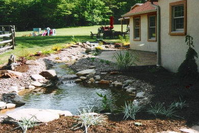 Inspiration for a large partial sun backyard concrete paver water fountain landscape in Philadelphia.