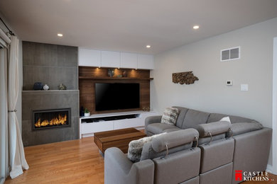This is an example of a medium sized modern mezzanine games room in Toronto with grey walls, light hardwood flooring, a standard fireplace, a tiled fireplace surround, a built-in media unit and beige floors.