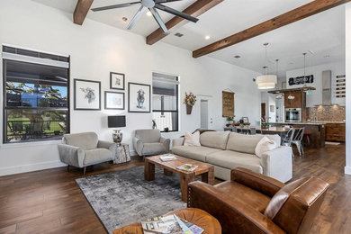 Example of a mid-sized farmhouse open concept medium tone wood floor, brown floor and exposed beam living room design in Austin with white walls, a standard fireplace, a stacked stone fireplace and a tv stand