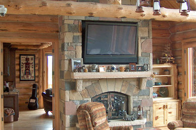 Inspiration for a large rustic enclosed light wood floor and brown floor family room remodel in Denver with brown walls, a two-sided fireplace, a stone fireplace and a wall-mounted tv