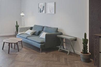 Design ideas for a mid-sized scandinavian formal open concept living room in London with white walls, dark hardwood floors, no fireplace, a freestanding tv and brown floor.