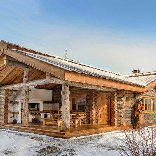 На фото: одноэтажные фасады частных домов коричневого цвета в стиле рустика с облицовкой из дерева и двускатной крышей