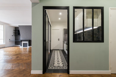 Photo of an expansive transitional foyer in Paris with green walls, light hardwood floors, a double front door and a black front door.