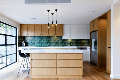 This is an example of a large contemporary l-shaped open plan kitchen in Melbourne with an undermount sink, recessed-panel cabinets, medium wood cabinets, granite benchtops, green splashback, ceramic splashback, black appliances, medium hardwood floors, with island and grey benchtop.