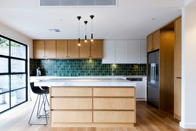 This is an example of a large contemporary l-shaped open plan kitchen in Melbourne with an undermount sink, recessed-panel cabinets, medium wood cabinets, granite benchtops, green splashback, ceramic splashback, black appliances, medium hardwood floors, with island and grey benchtop.