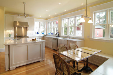 Mid-sized elegant u-shaped light wood floor and beige floor eat-in kitchen photo in Other with a farmhouse sink, shaker cabinets, white cabinets, quartzite countertops, white backsplash, stone slab backsplash, stainless steel appliances and an island