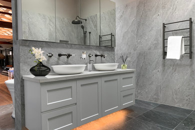 Photo of a master bathroom in Sydney with shaker cabinets, white cabinets, gray tile, porcelain tile, porcelain floors, a vessel sink, solid surface benchtops, grey floor, white benchtops, a double vanity and a floating vanity.