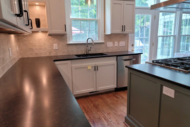 Photo of a mid-sized traditional l-shaped kitchen pantry in Raleigh with an undermount sink, shaker cabinets, solid surface benchtops, beige splashback, porcelain splashback, stainless steel appliances, medium hardwood floors, with island and brown benchtop.