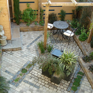 Kleiner, Halbschattiger Stilmix Garten im Sommer, hinter dem Haus mit Sportplatz und Natursteinplatten in Kent