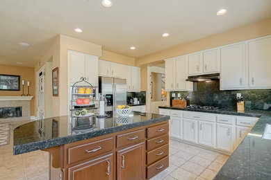 Inspiration for a mid-sized timeless l-shaped ceramic tile and beige floor eat-in kitchen remodel in San Diego with a double-bowl sink, recessed-panel cabinets, white cabinets, granite countertops, black backsplash, stone tile backsplash, stainless steel appliances and an island