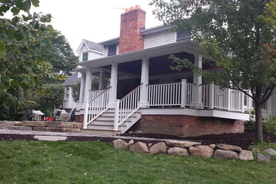Example of a large arts and crafts backyard deck design in Detroit with a roof extension