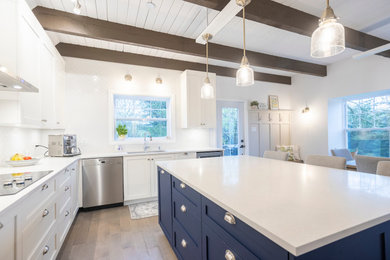 Example of a large transitional u-shaped light wood floor, multicolored floor and exposed beam eat-in kitchen design in Montreal with an undermount sink, shaker cabinets, white cabinets, quartzite countertops, white backsplash, ceramic backsplash, stainless steel appliances, an island and white countertops