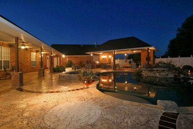 Patio kitchen - mid-sized tropical backyard stamped concrete patio kitchen idea in Dallas with a roof extension