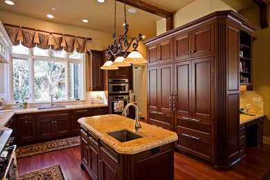 Example of a huge classic u-shaped dark wood floor and beige floor open concept kitchen design in San Francisco with an undermount sink, beaded inset cabinets, dark wood cabinets, granite countertops, beige backsplash, stone tile backsplash, paneled appliances, two islands and beige countertops