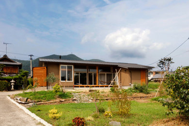 Ejemplo de fachada de casa marrón y gris de una planta con tejado a dos aguas y tejado de metal