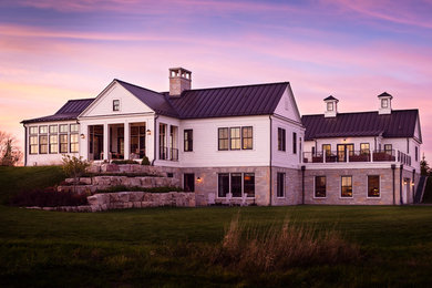 Large trendy white two-story exterior home photo in Milwaukee with a metal roof