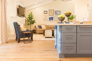 Example of a mid-sized transitional medium tone wood floor and beige floor open concept kitchen design in Phoenix with an undermount sink, shaker cabinets, white cabinets, quartzite countertops, gray backsplash, ceramic backsplash, stainless steel appliances and an island