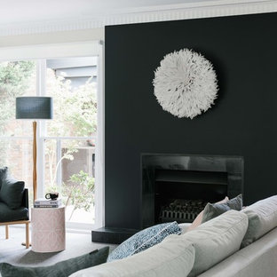 This is an example of a mid-sized transitional open concept family room in Melbourne with black walls, carpet, a standard fireplace, a tile fireplace surround and grey floor.