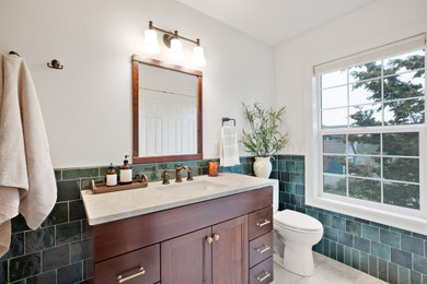 Inspiration for a mid-sized craftsman 3/4 green tile and ceramic tile ceramic tile, beige floor and single-sink bathroom remodel in Portland with furniture-like cabinets, brown cabinets, a one-piece toilet, gray walls, a drop-in sink, quartzite countertops, beige countertops, a niche and a built-in vanity