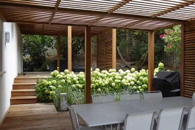Modelo de terraza marinera grande con jardín de macetas, pérgola y barandilla de madera