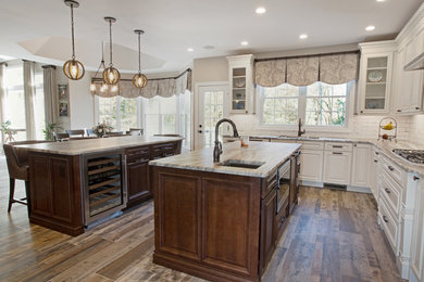 Inspiration for a large country l-shaped open plan kitchen in Philadelphia with an undermount sink, raised-panel cabinets, distressed cabinets, quartzite benchtops, white splashback, ceramic splashback, stainless steel appliances, porcelain floors, multiple islands, brown floor and multi-coloured benchtop.