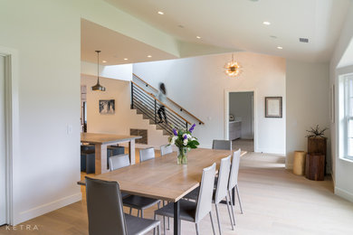 Large trendy light wood floor and beige floor kitchen/dining room combo photo with white walls
