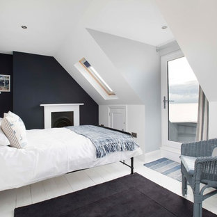 Großes Maritimes Hauptschlafzimmer mit weißer Wandfarbe, gebeiztem Holzboden, Kamin, Kaminumrandung aus Metall und weißem Boden in Kent