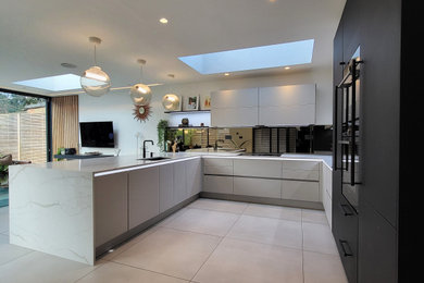Inspiration for a large contemporary u-shaped kitchen/diner in Essex with a submerged sink, recessed-panel cabinets, beige cabinets, marble worktops, mirror splashback, black appliances, porcelain flooring, a breakfast bar, beige floors and yellow worktops.