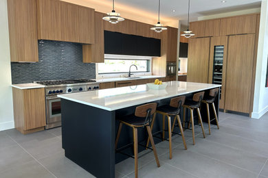 Open concept kitchen - large modern l-shaped ceramic tile and gray floor open concept kitchen idea in Cincinnati with an undermount sink, flat-panel cabinets, light wood cabinets, quartz countertops, green backsplash, ceramic backsplash, paneled appliances, an island and white countertops