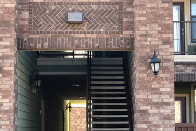 ダラスにある広いトラディショナルスタイルのおしゃれな直階段 (コンクリートの蹴込み板、金属の手すり、レンガ壁) の写真