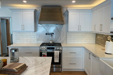 Inspiration for a mid-sized country u-shaped medium tone wood floor, beige floor and exposed beam eat-in kitchen remodel in Toronto with a farmhouse sink, raised-panel cabinets, white cabinets, quartz countertops, brown backsplash, brick backsplash, stainless steel appliances, an island and white countertops