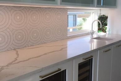 Inspiration for a mid-sized contemporary single-wall light wood floor kitchen remodel in Orange County with a single-bowl sink, flat-panel cabinets, white cabinets, marble countertops and white backsplash
