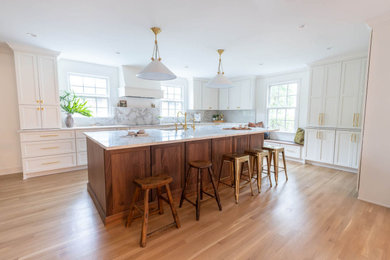 Kitchen - huge transitional light wood floor and beige floor kitchen idea with an undermount sink, flat-panel cabinets, white cabinets, quartzite countertops, white backsplash, white appliances, an island and white countertops