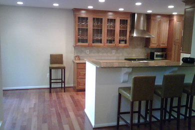 Example of a medium tone wood floor kitchen design in DC Metro with medium tone wood cabinets, beige backsplash and stainless steel appliances