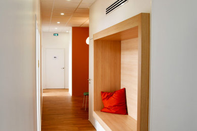 Idée de décoration pour un grand couloir design avec un mur blanc, un sol en linoléum et un sol marron.