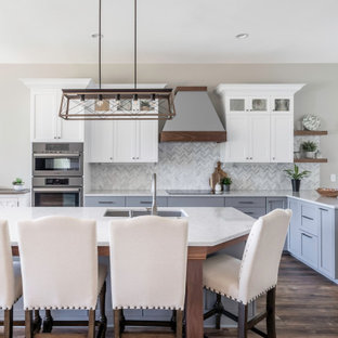 Foto di una grande cucina classica con lavello a doppia vasca, ante in stile shaker, ante bianche, top in quarzo composito, paraspruzzi bianco, paraspruzzi in marmo, elettrodomestici in acciaio inossidabile, pavimento in vinile, pavimento marrone e top bianco