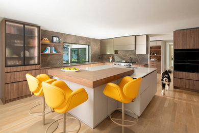 Kitchen - mid-sized contemporary l-shaped light wood floor and beige floor kitchen idea in Dallas with an undermount sink, flat-panel cabinets, solid surface countertops, brown backsplash, an island, white countertops, medium tone wood cabinets, stone slab backsplash and black appliances