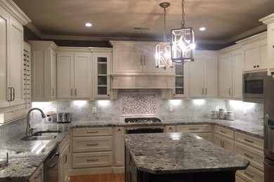 Example of a mid-sized classic u-shaped light wood floor eat-in kitchen design in Atlanta with an undermount sink, flat-panel cabinets, white cabinets, granite countertops, gray backsplash, marble backsplash, stainless steel appliances and an island