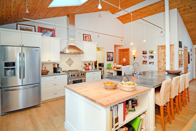 Mid-sized arts and crafts single-wall light wood floor and brown floor eat-in kitchen photo in Seattle with a farmhouse sink, shaker cabinets, white cabinets, white backsplash, ceramic backsplash, stainless steel appliances, an island and quartzite countertops