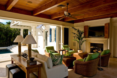Example of a mid-sized island style open concept family room design in Miami with white walls, a standard fireplace, a wood fireplace surround and a wall-mounted tv