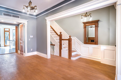 Medium tone wood floor and multicolored floor great room photo in New York with multicolored walls, a standard fireplace and a wood fireplace surround