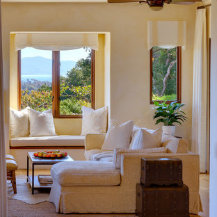Mittelgroßes Mediterranes Wohnzimmer mit gelber Wandfarbe, Bambusparkett, Kamin, Kaminsims aus Stein und Wand-TV in Santa Barbara
