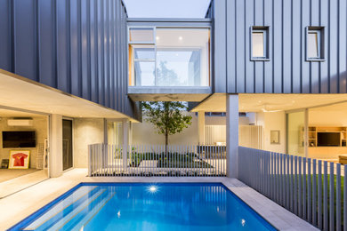 This is an example of a mid-sized modern verandah in Perth with an outdoor kitchen, natural stone pavers and a roof extension.